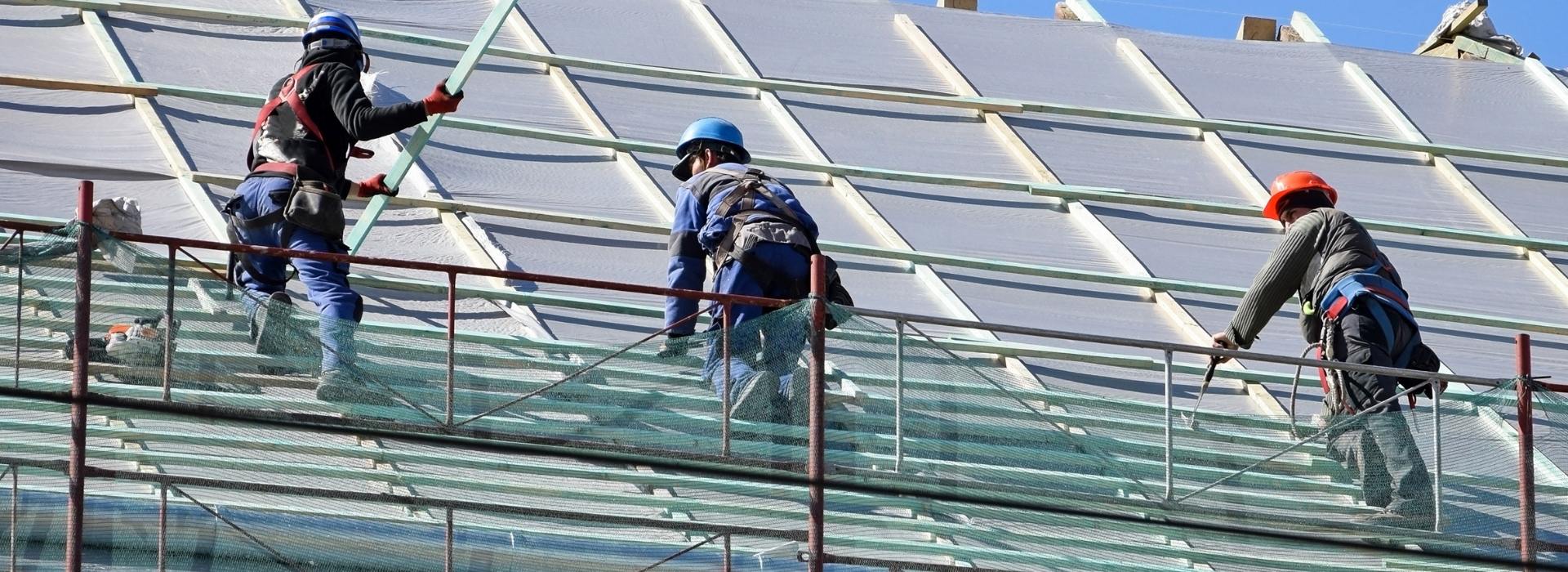 Image depicts roofers working on a roof for a commercial building.